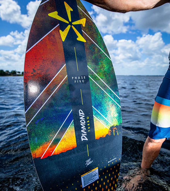 Colorful wakesurf board with a person standing on a boat swim deck.